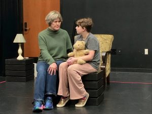 two people sitting in a chair on stage at SPSCC production of 'Far Away'