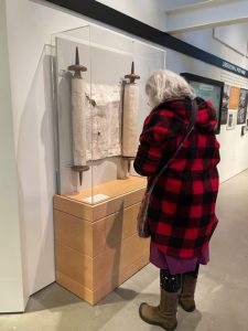 person standing by an old scroll manuscript at an exhibit