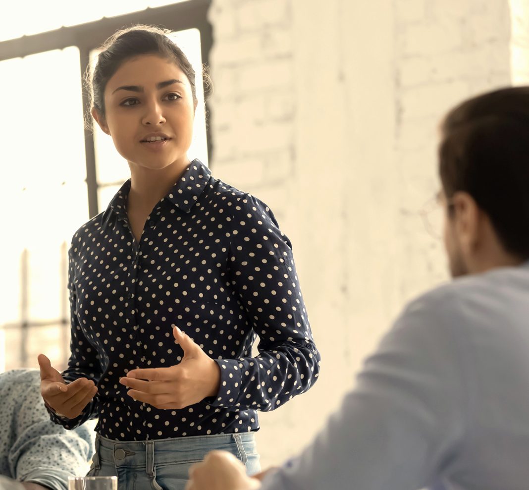 woman standing talking to a man who is sitting