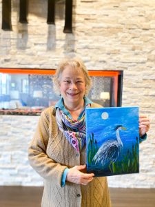 Maia holding up a panting of a heron she did at Harbor Heights apartments in Olympia