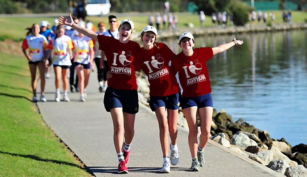 People in matching shirts running along side a pond