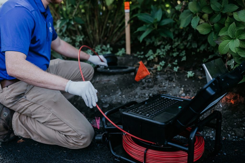 Boggs Inspection Services Tech kneeling down using a sewer scope