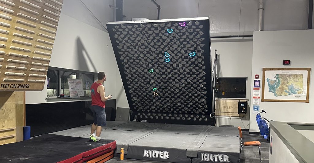 Jimmy Chulich in front of the kilter wall at Cirque Climbing Gym in Lacey