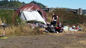 homeless camp with a tent in the grass