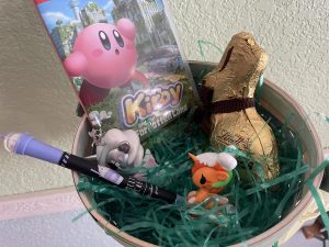 Easter basket with fake grass, a bubble tea ben, a Kirby Switch game, a Lindy chocolate bunny and two Tokido blind box unicorns