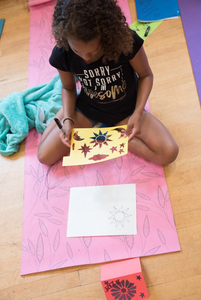 Young girl kneeling on the floor working on a drawing.