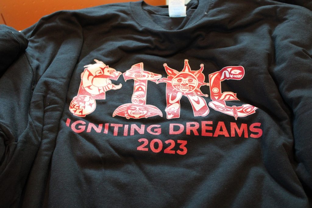FIRE Summit black t-shirt with the words "FIRE Igniting Dreams 2023" in red