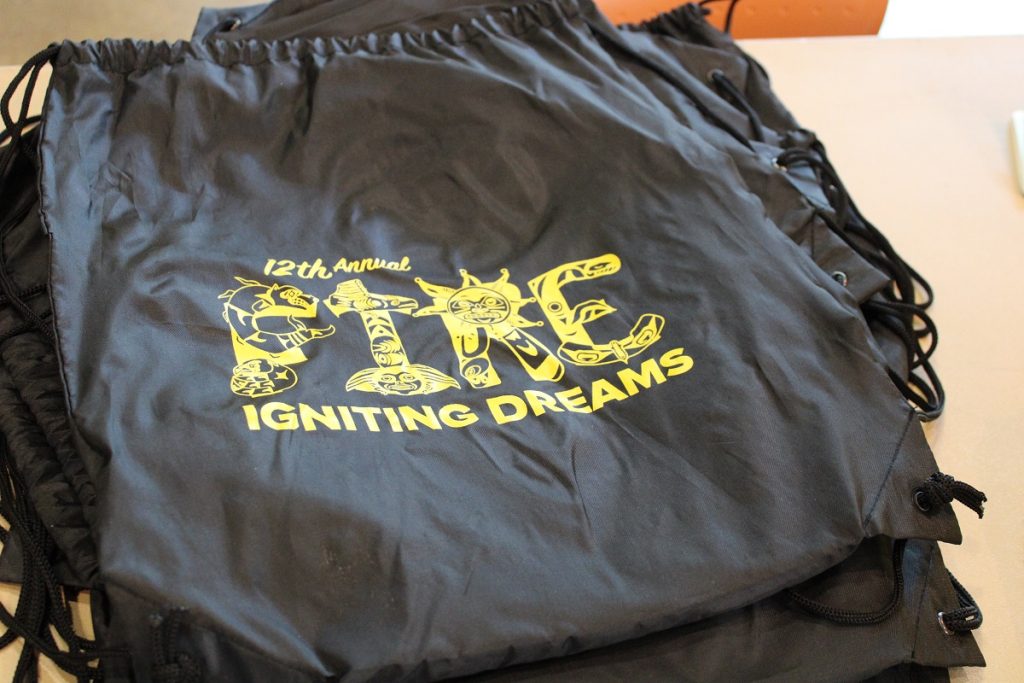 black nylon drawstring bag with the words "FIRE Igniting Dreams" in yellow