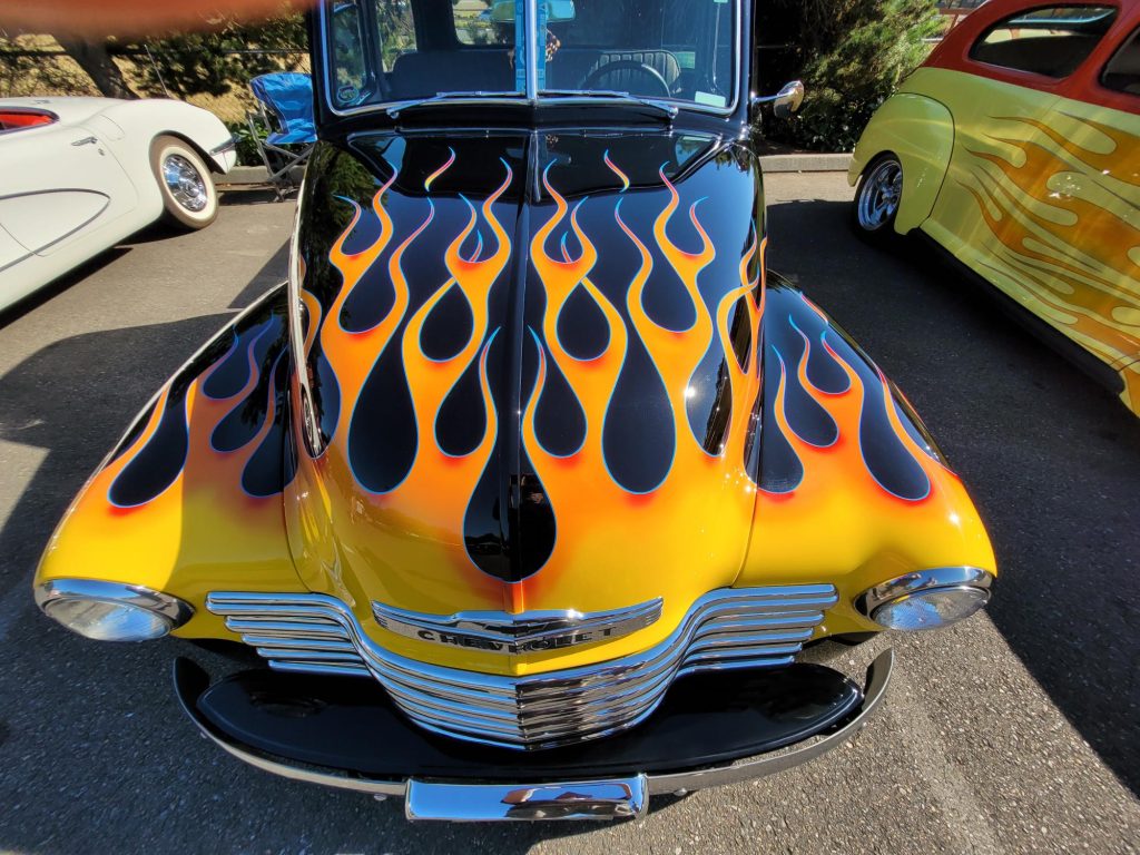 classic convertible hot rod with with a yellow and orange flame paint job on it's hood
