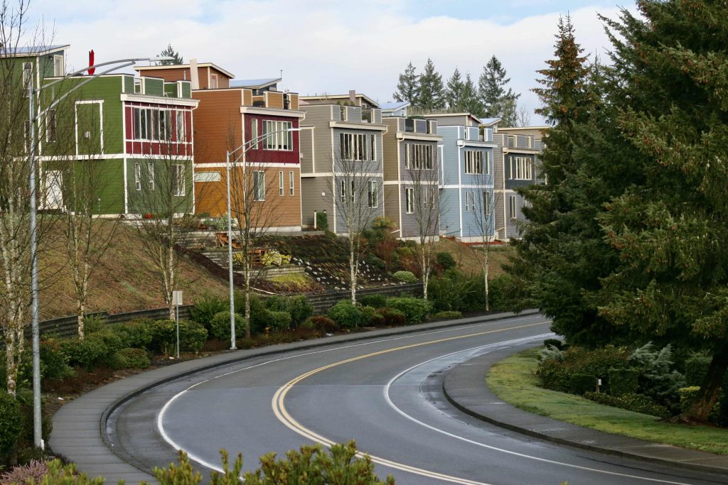 a street with bend in it, with homes in the background