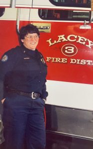 Maggie Bean in her firefighter uniform standing by a fire engine