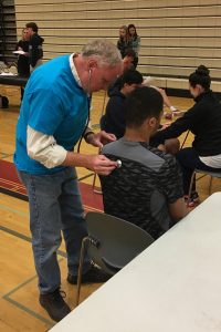 Dr. Peterson checking the lungs of a teenager at a sports physical