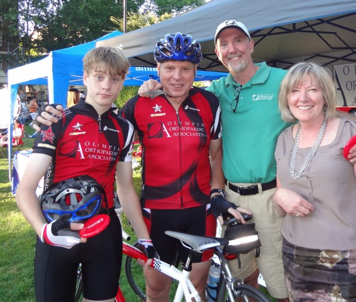 r. Peterson smiling with three other people around a mountain bike