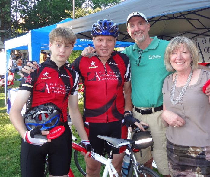 OlyOrtho-Dr-Peterson-retirement-biking r. Peterson smiling with three other people around a mountain bike