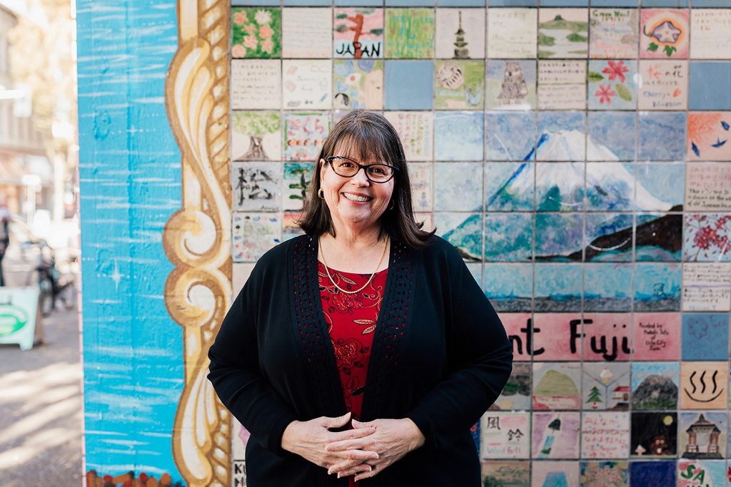 Barbara Whitlow standing in front of a mural on a wall