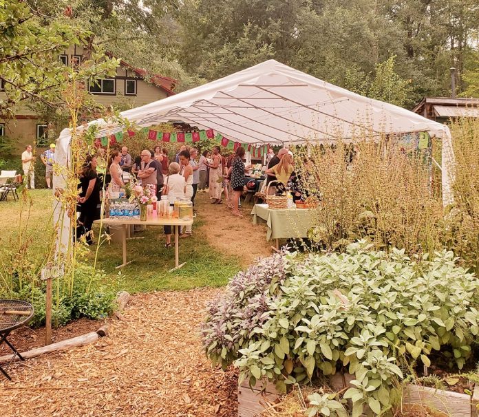 large white open air tent with a gathering going on inside in the garden at GRuB