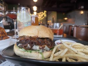 Cynara's onion burger and fries on a black plate