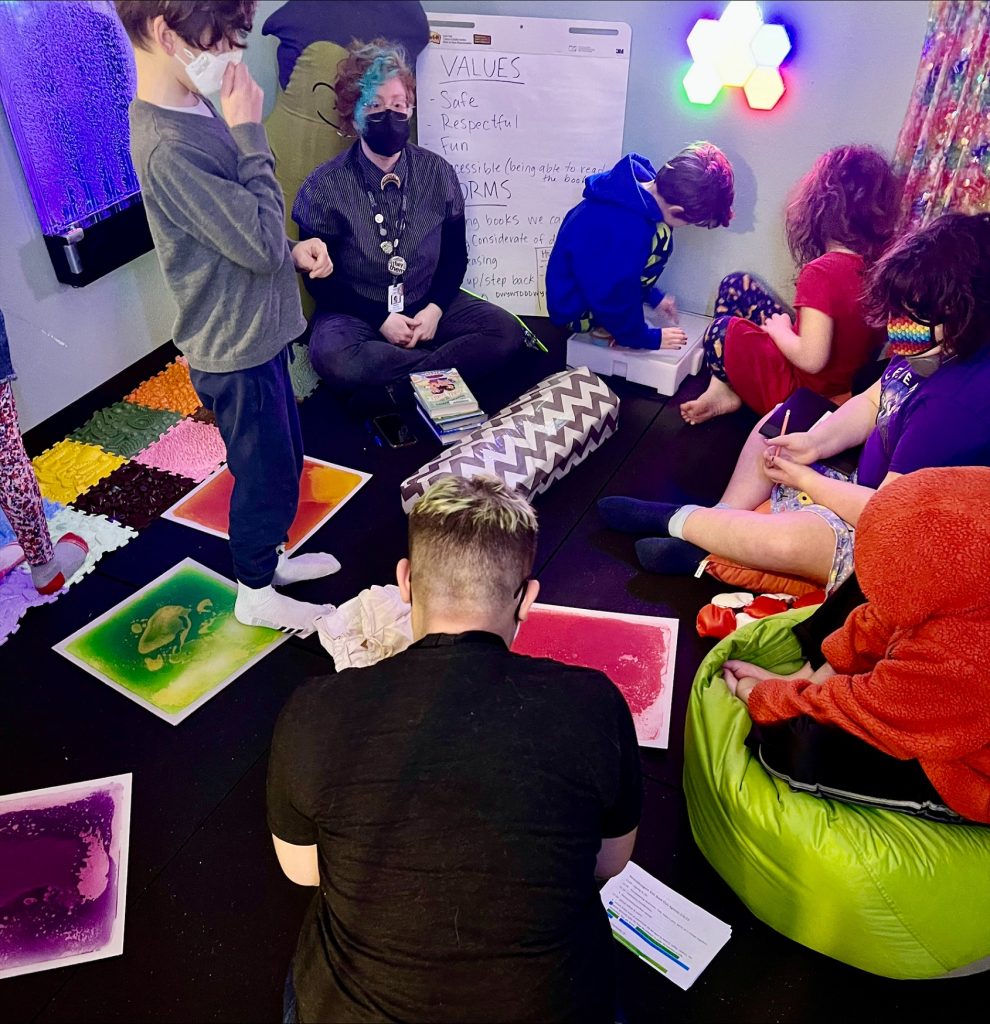a group of kids an adults sitting on the floor doing various activities at Sensory Tool House