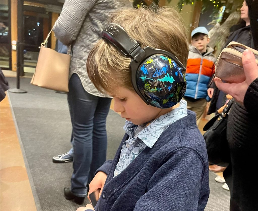 young child with noise-canceling headphones on in a public place