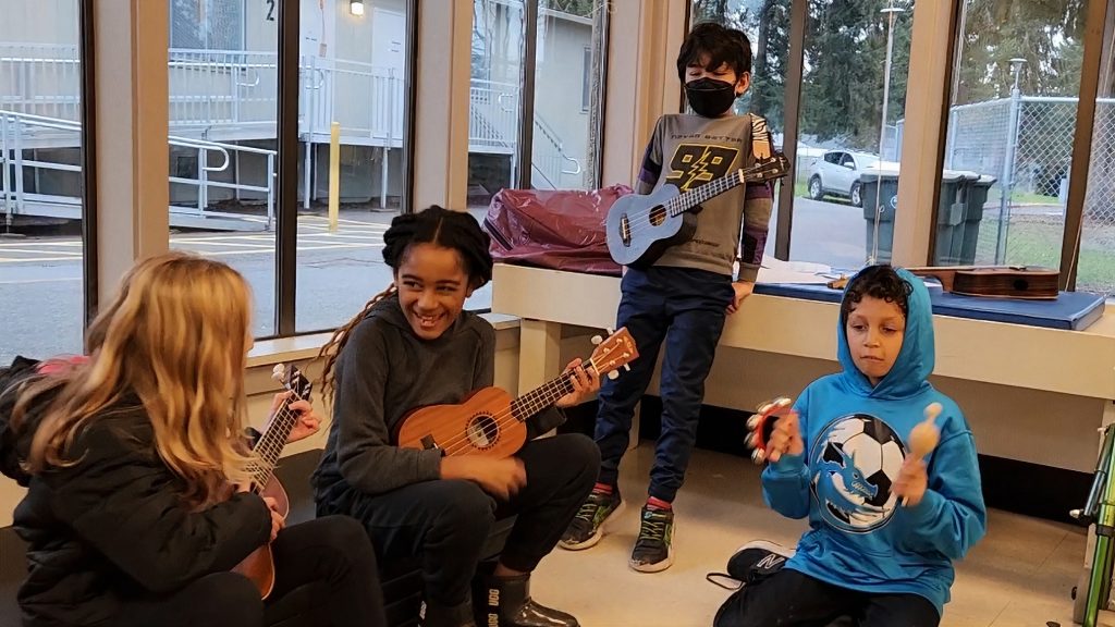 a woman playing the ukulele for a group of kids