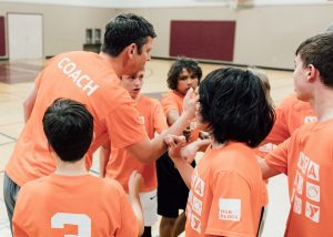 coach talking to a group of kids on a basketball court