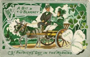 Historic postcard in shades of green with a couple in a mule care with the words, 'A bit of o'blarney. St. Patrick's Day in the Morning.'