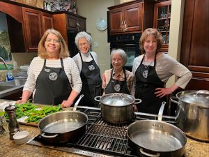 The Bayview School of Cooking team standing behind a stove with pots and pans on it