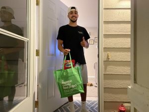 man at his door giving the thumbs up while holding a Thurston County Food Project green bag