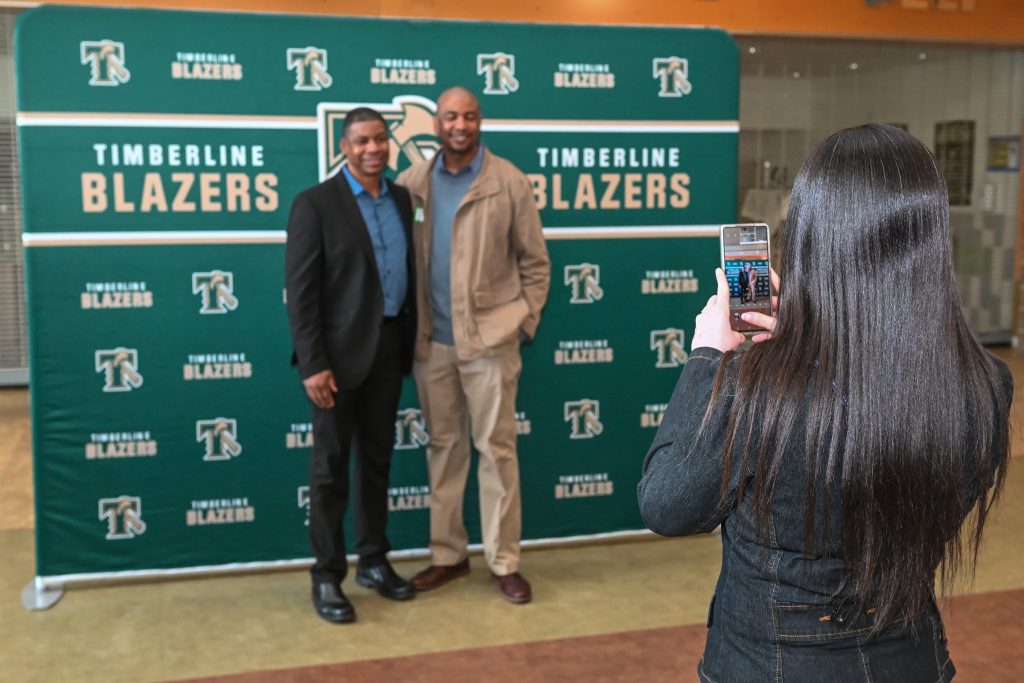 People standing in front of a step-and-repeat at the Timberline High School's Athletic Hall of Fame Induction Ceremony