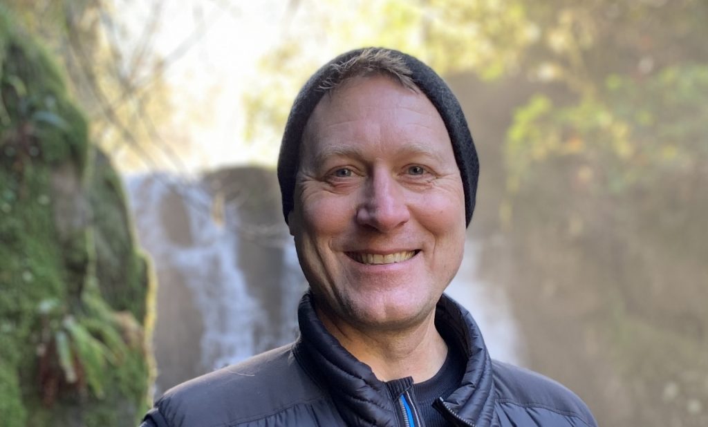 Kevin Bogatin on a hike with a waterfall behind him.