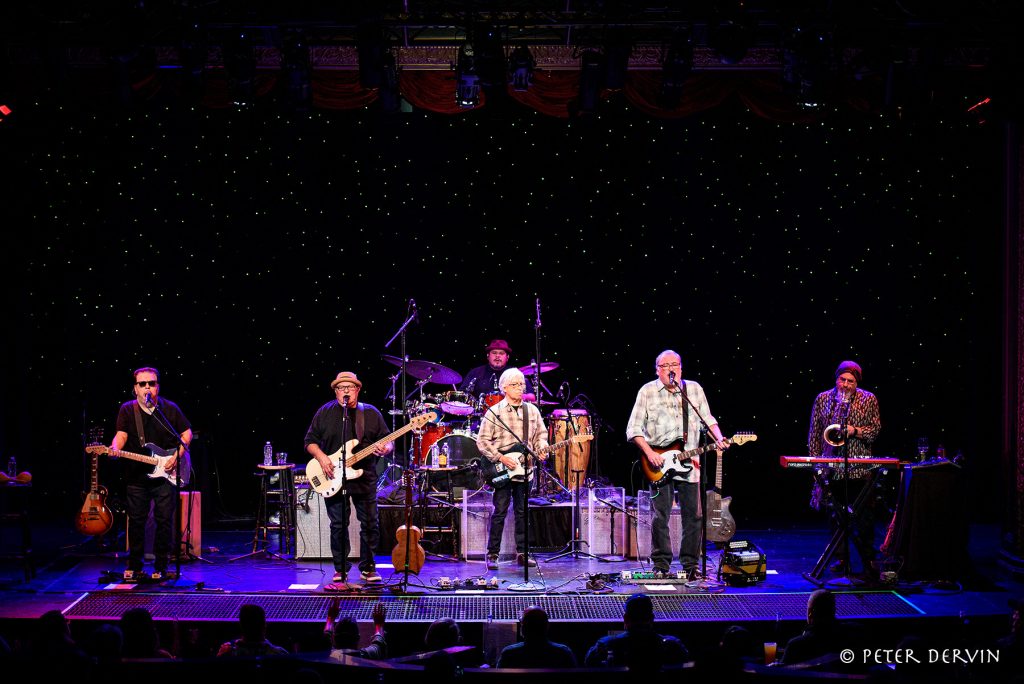 Los Lobos performing on a dark stage