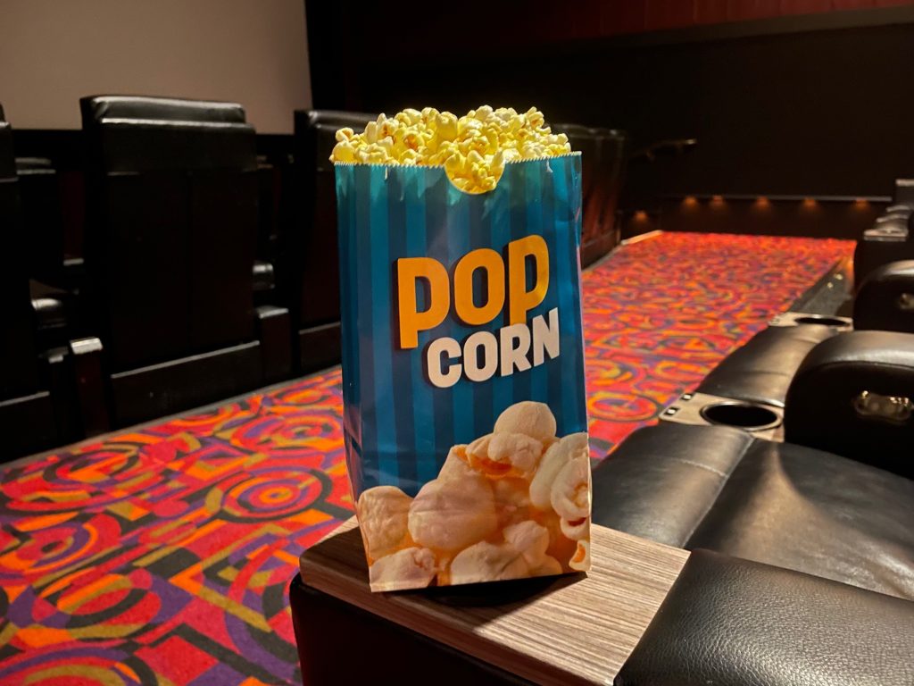 bag of popcorn sitting on the armrest of a reclining seat at Cinemark Theatres