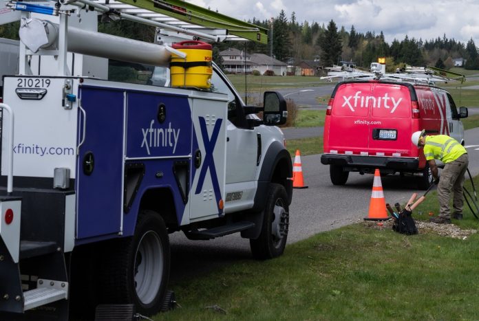 comcast Comcast and Xfinity trucks with men working by roadway