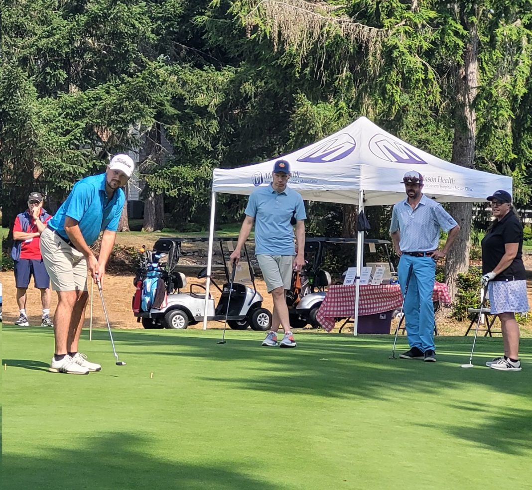 People playing golf with a white pop-up tent in the background