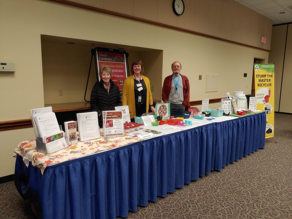 WSU Master Gardeners standing behind a table with all sorts of gardening handouts and information.