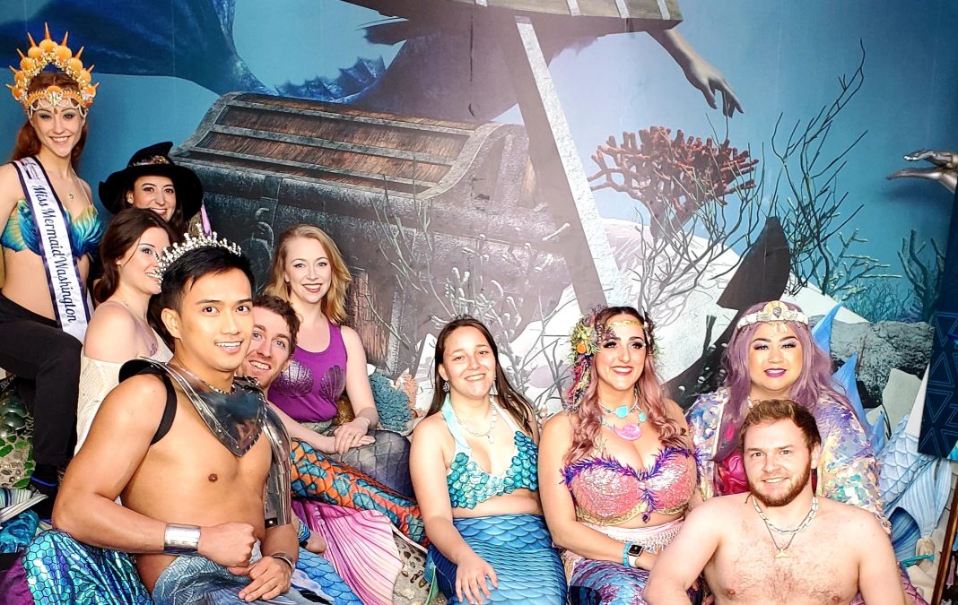 a group of people dressed as mermaids in front of a sunken ship backdrop photo