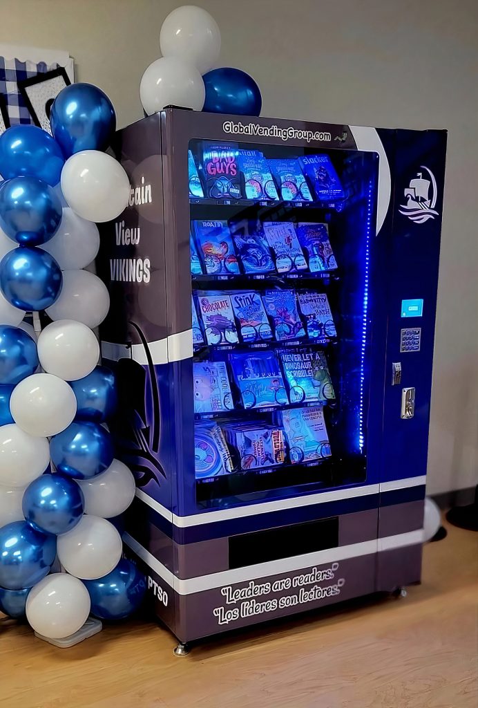 book vending machine with blue and white balloon chain next to it at Shelton's Mountain View Elementary