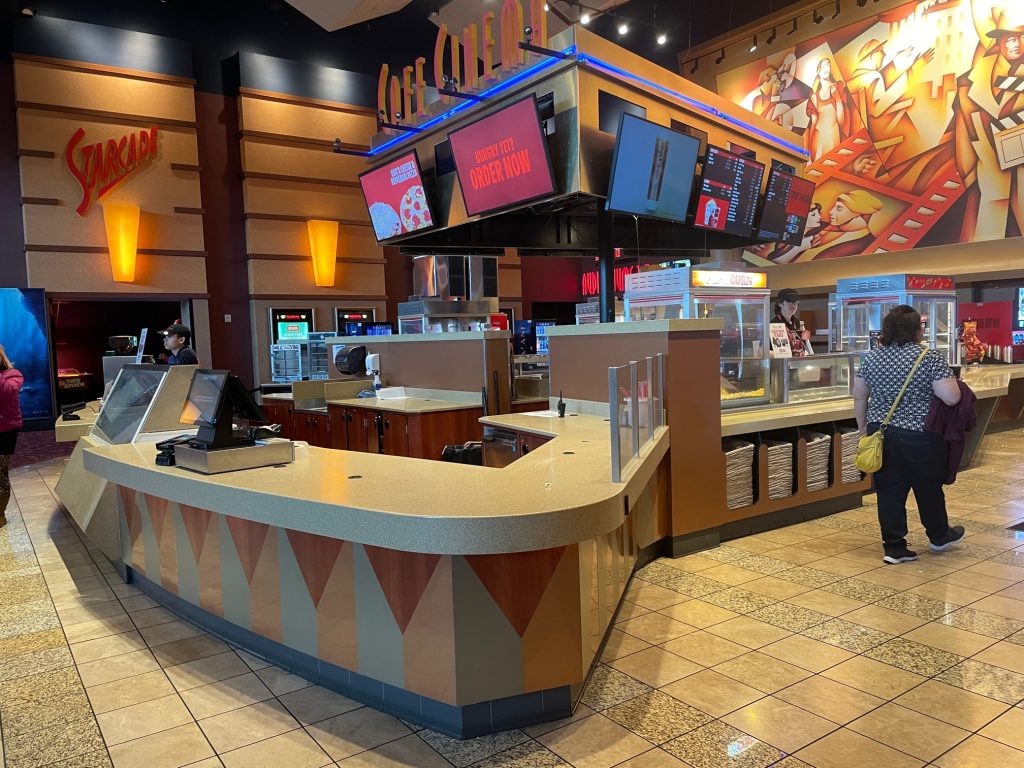 Concession stand with a couple works and one customer at Cinemark Theatres