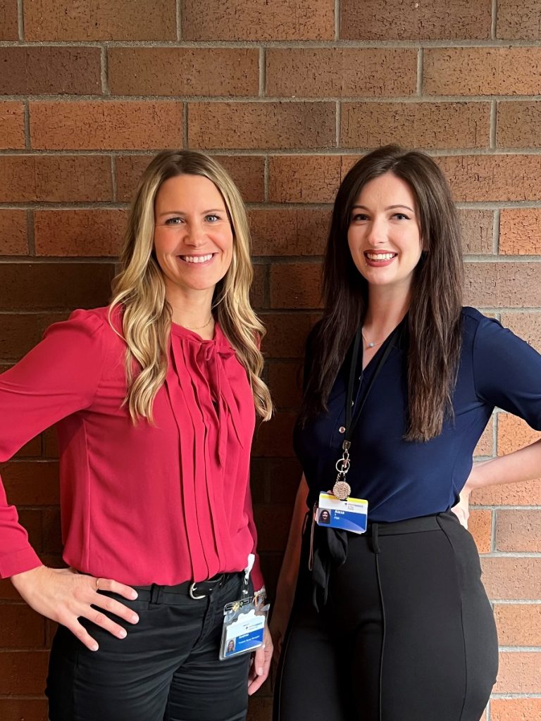 Andrea Potter and Alexa Templeton standing by a brick wall