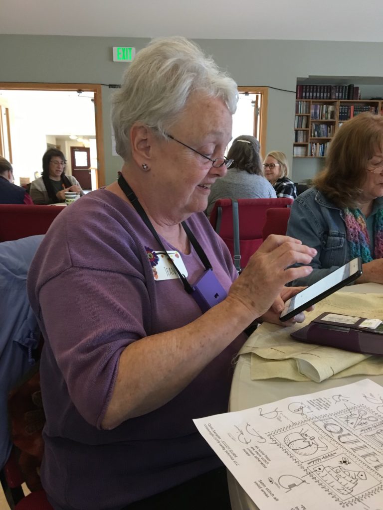 Jean Sheffield sitting at a table hand quilting