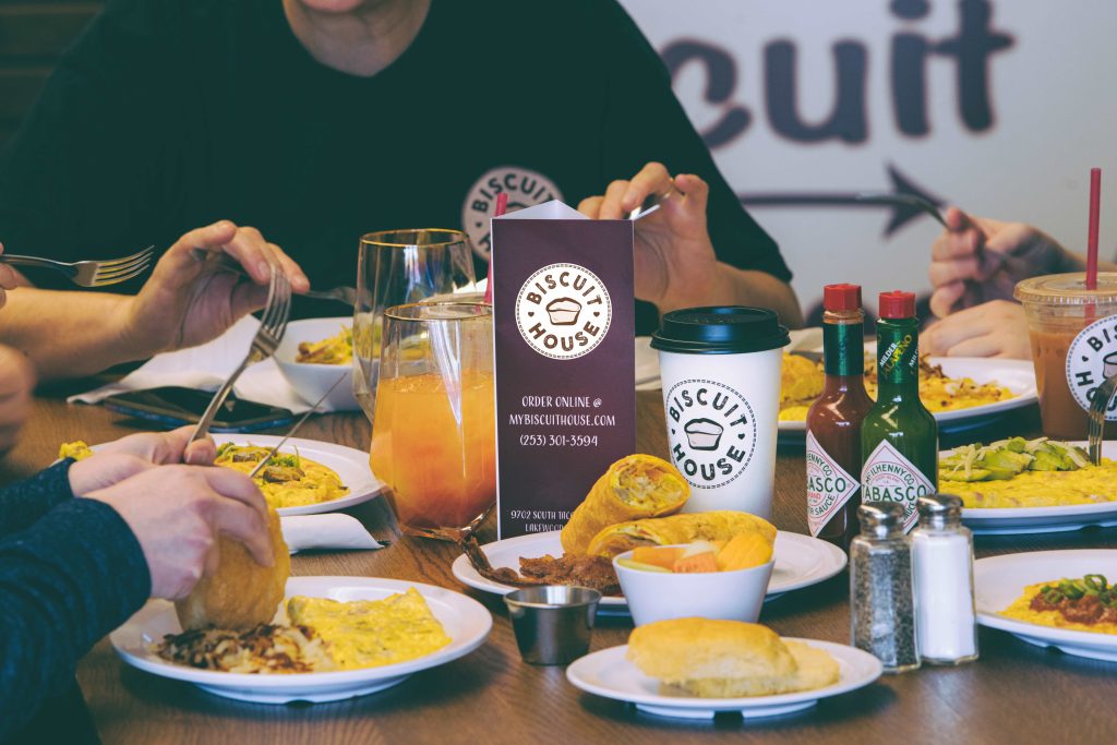 close up a table full of breakfast food at Biscuit House Tumwater with people eating at it.