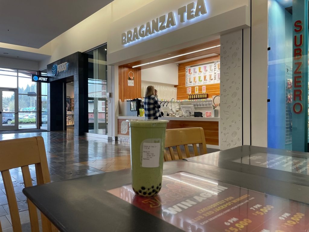 matcha bubble tea on a table in the Capital Mall with the Braganza Tea shop behind it