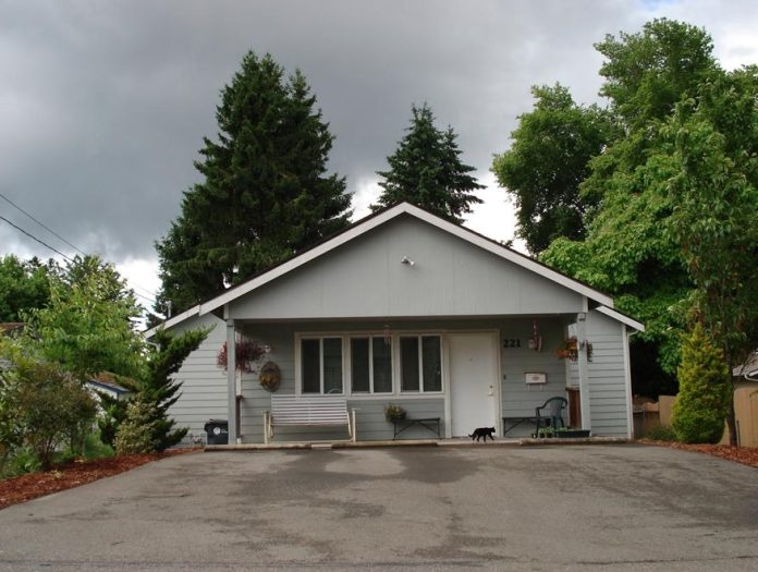 Homes First DD Home Milroy Street Grey house with a large driveway and trees behind it