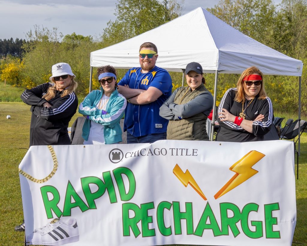 A group of people with their arms crossed stand behind a banner that says, 'Chicago Title: Rapid Recharge'