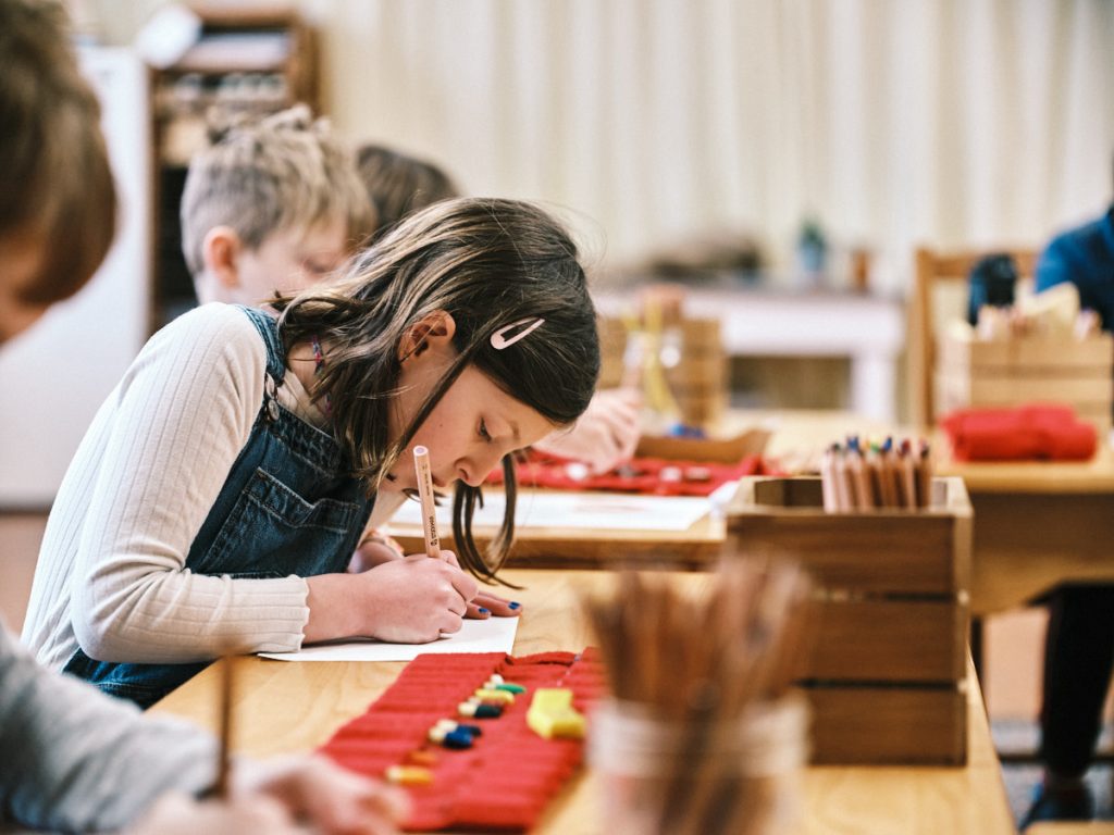 young students sitting at large desks writing with pencils on paper
