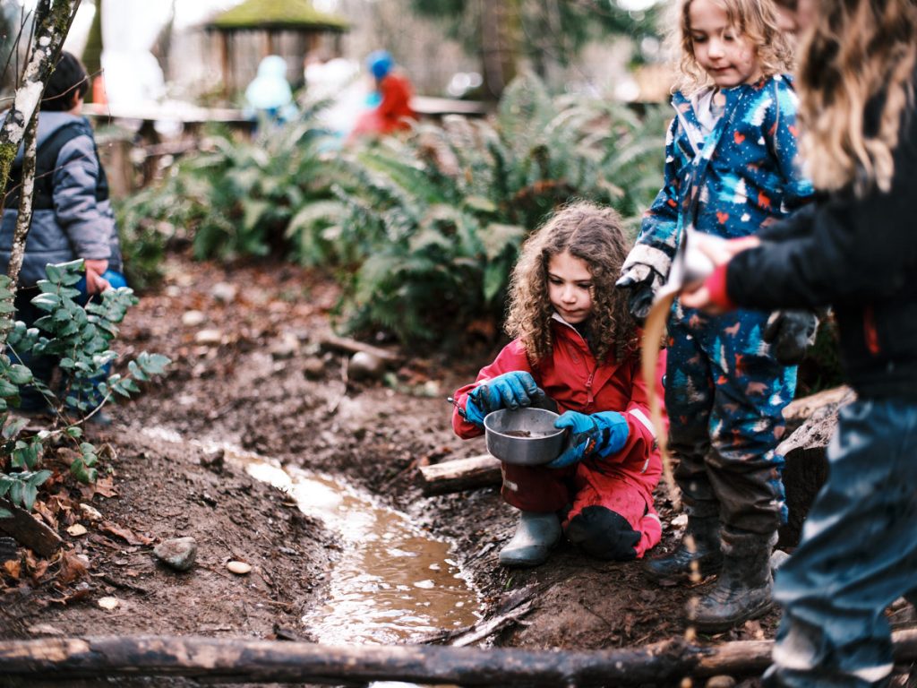 Kids playing outside in dirt and bushes