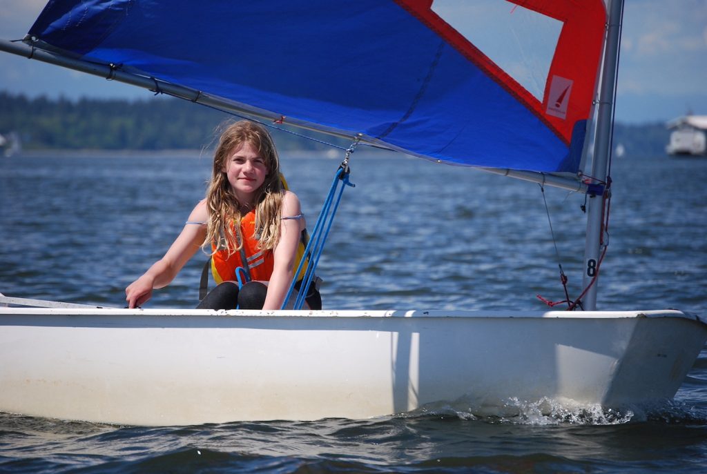 Girl in a sailboat with a red, white and blue sail