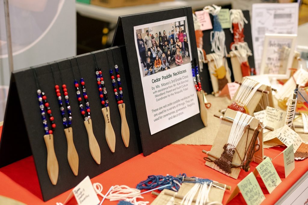a table with information about Billy Frank Jr. Day and some beaded necklaces on display