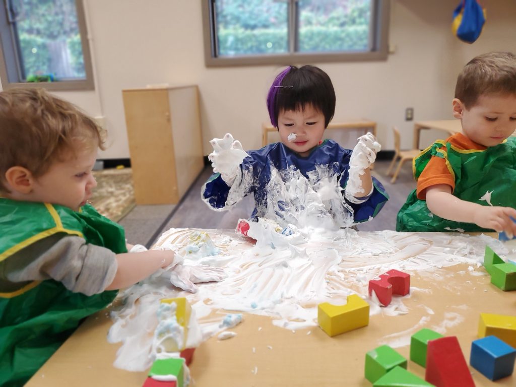 Kids playing with white flour at a table with blocks
