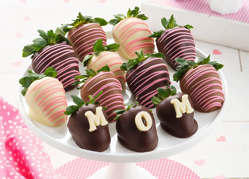 white, milk and dark chocolate-dipped strawberries with pink icing with three strawberries spelling out "Mom" with chocolate letters